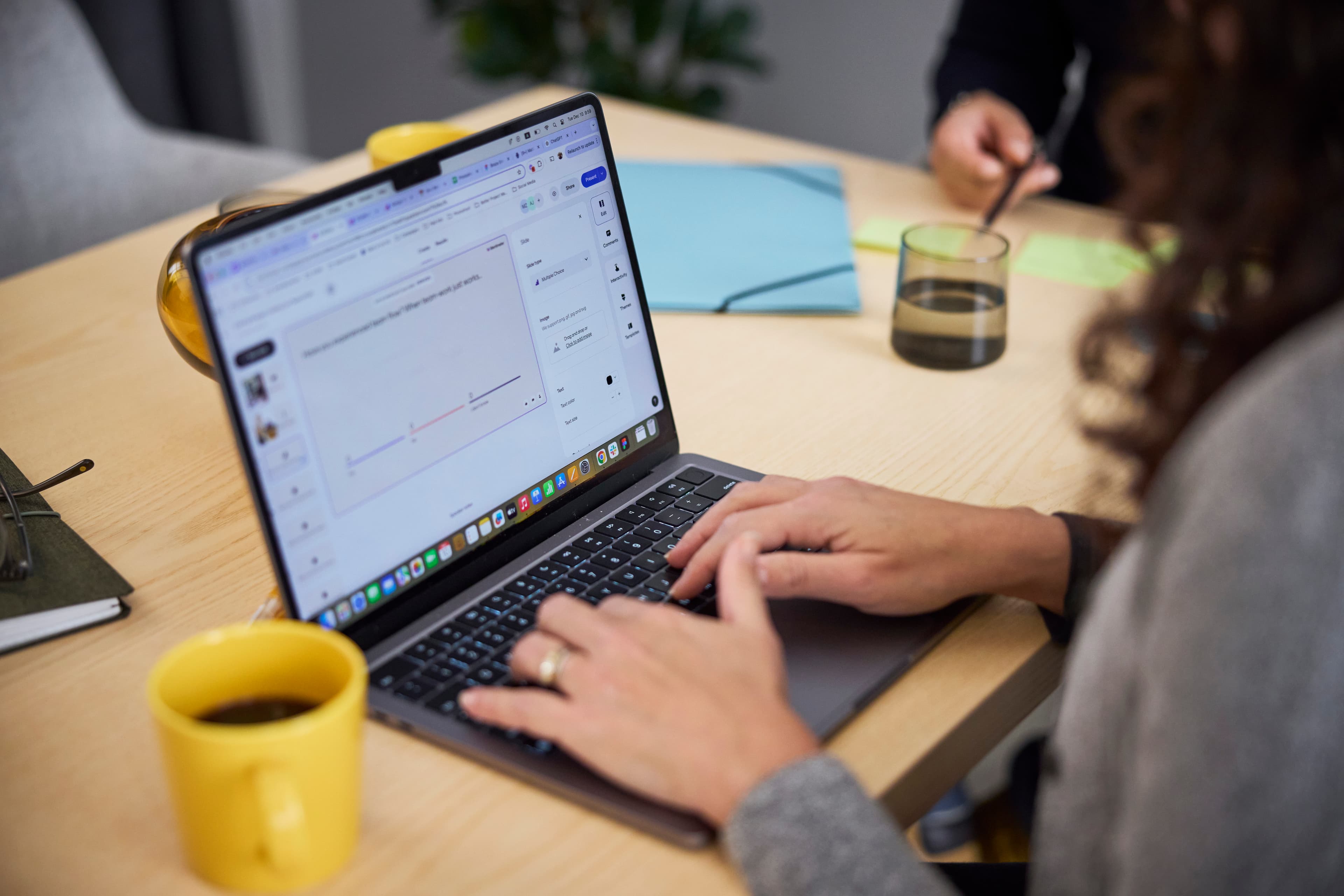 Hands typing on a laptop with yellow coffee cup